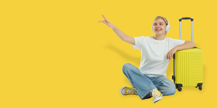Travel. Young woman sits next to yellow suitcase, smiling and gesturing with excitement