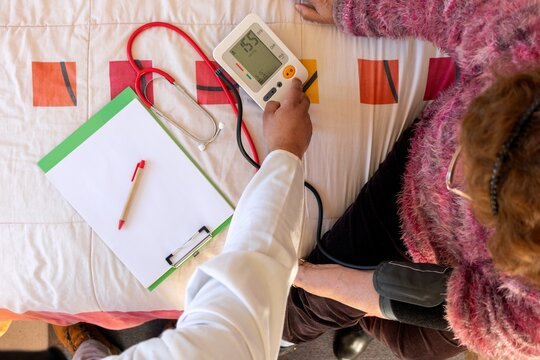 Healthcare worker checking senior woman's blood pressure
