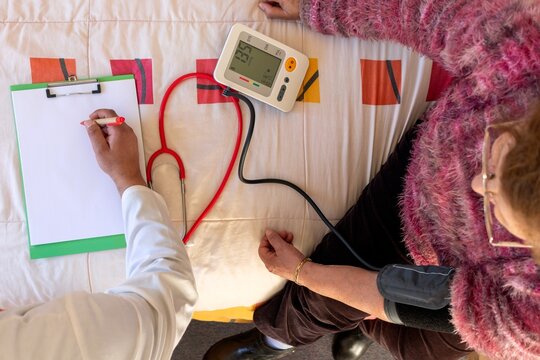 Over head Doctor checking senior woman's blood pressure at home