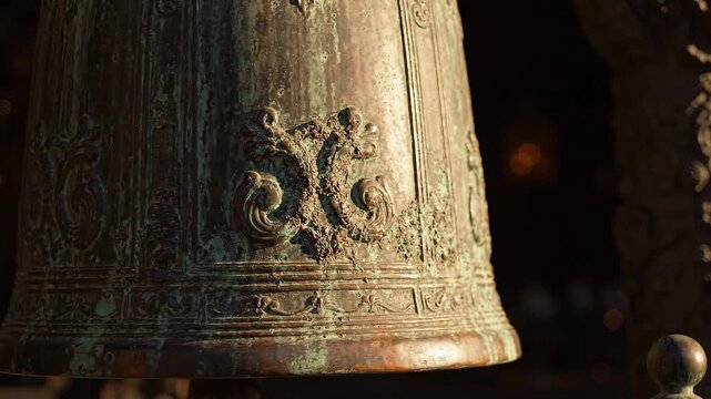 Ancient bronze temple bell with ornate engraving and green patina swinging slowly. Historical religious artifact detail and cultural heritage concept