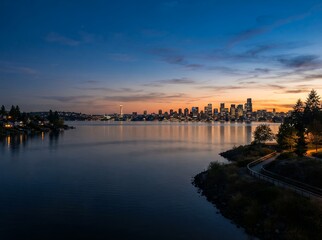 Naklejka premium Vancouver Cityscape at Dusk Over Water with Trees and Mountains.