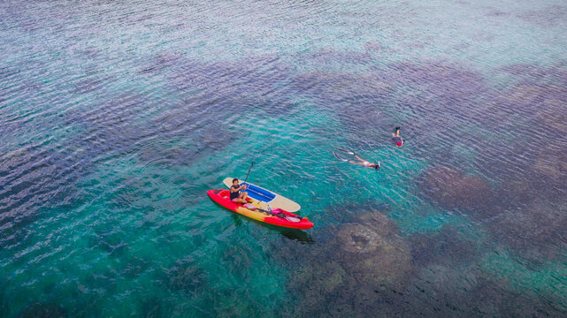 Top aerial view of Group of tourist are enjoy on water sport paddle sup-board with kayaking along at the edge of the sea beach under crystal clear of water in the island of summer trip