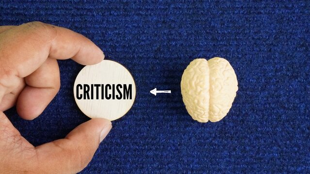 The human brain with the word criticism. opinion or judgment about the good and bad qualities of someone or something.