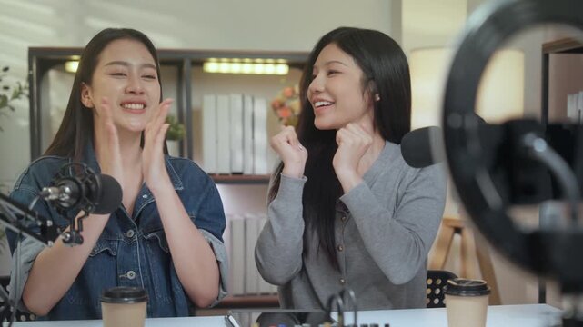 Podcast digital creator home studio microphone recording audio female smile with two women cohosts chat over coffee, mixer, soft light, ring light, smartphone, live interview, camera at desk
