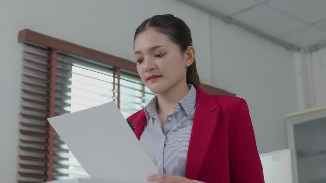 Asian businesswoman reading corporate document in office