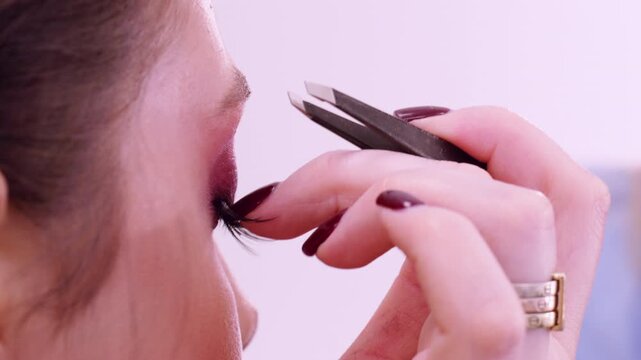 Tweezers makeup using. Woman beauty. Beautician expert applying false eyelashes for cosmetic treatment extension procedure.