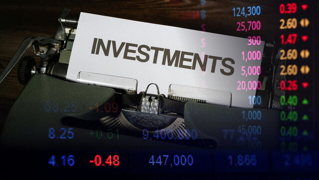 Financial planning and stock market investment strategy concept. Vintage typewriter with word Investments printed on white paper overlaying digital stock exchange chart data and ticker numbers 