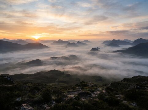 Sunrise over misty mountains with sun rays breaking through clouds.