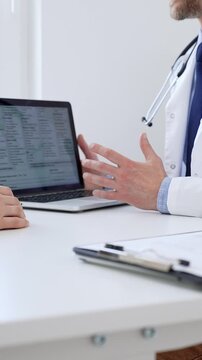 Doctor reviewing digital test results with patient, discussing health findings on laptop screen during clinical consultation. Medicine and health care concept.