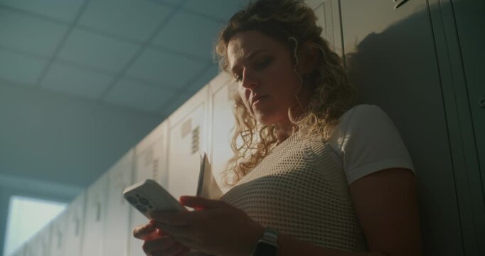 Teacher Enjoying Quiet Moment in Empty Locker Area While Browsing Social Media on Smartphone. Concept of Work Life Balance, Digital Habits, and Everyday Routines Inside Educational Institution.