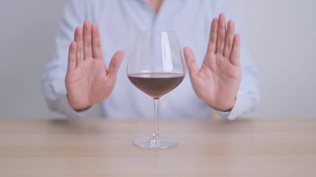 man making stop hand gesture to refuse a glass of Wine, Healthy man say no to alcohol drink, stop alcoholism and addiction concept. Responsible man reject a drink before driving and quit booze