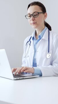 Female doctor is typing on a laptop in a bright medical office, showcasing healthcare technology and medical documentation. Medicine and health care concept