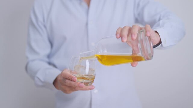 man pour whiskey into a glass on table, suffering from alcohol addiction, alcoholism concept. depicting emotional distress, depression, substance abuse problem, unhealthy lifestyle and mental health