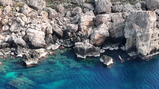 jagged limestone boulders rocky coastline malta clear turquoise water aerial drone erosion tidal pool coastal texture rugged shoreline mediterranean karst