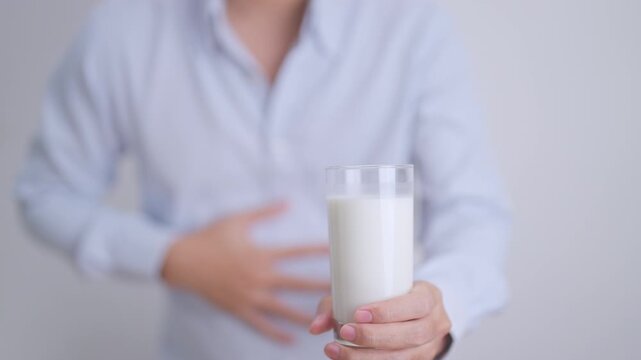 Lactose intolerance and Milk allergy concept. man with Milk glass and having abdominal cramps and pain when drink Cow Milk. Symptom stomach ache, Dairy intolerant, Nausea, Bloating, Gas and Diarrhea