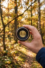 Naklejka premium Hand Holding Camera Lens Framing Forest View in Nature Photography