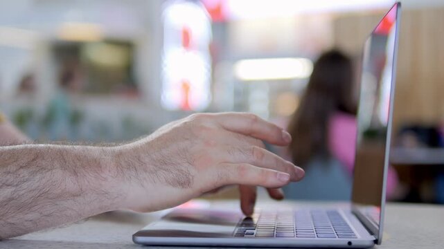 Man's hands type on laptop keyboard. Background blurred, focused on typing action. Ideal for remote work, online meetings, or digital productivity themes