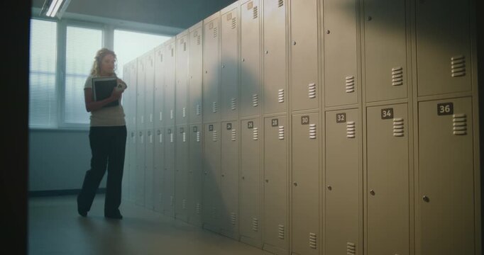 Exhausted Female Teacher Pauses Alone in School Locker Room after Busy Day with Students. Leaning Against Lockers, Woman Takes Brief Moment to Recharge before Returning Educational Responsibilities.