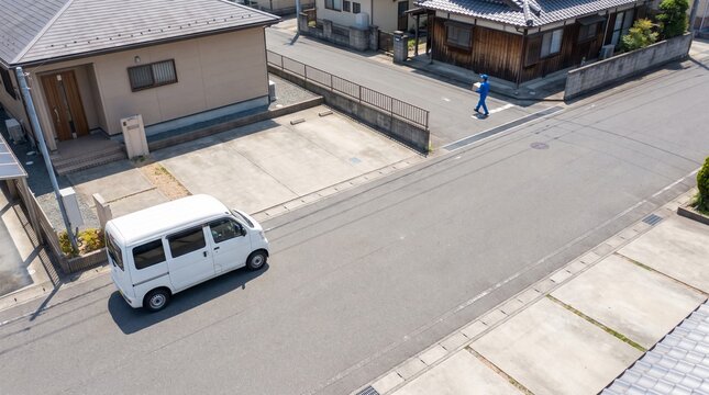 住宅街で宅配便を届ける配送車とラストワンマイル物流