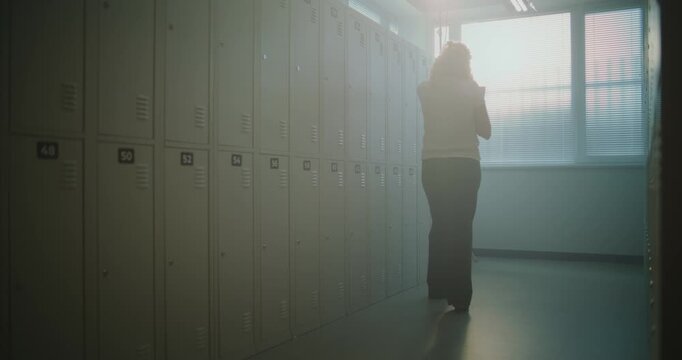 School Teacher Stands Silently in Empty Hallway Locker Area, Catching Breath after Intense Schedule of Lessons, Student Interactions. Burnout Prevention, Stress Management, Mental Wellness in Schools.
