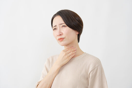 白背景で喉の痛みに苦しむ40代女性