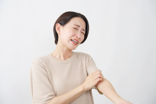 白背景で腕のかゆみに悩む40代女性