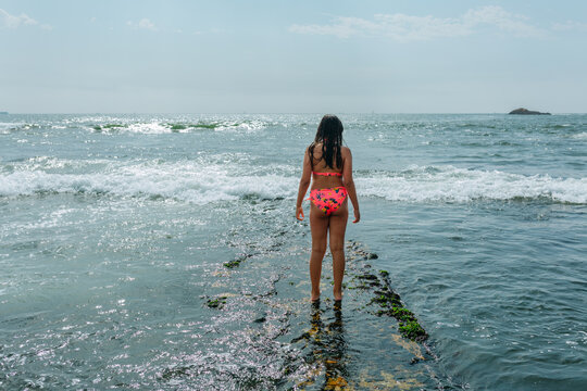 Rear View of Young Girl Walking on a Rocky Shore at Low Tide