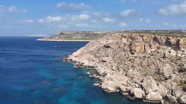 bluff jagged limestone headland pinnacle rocky point overlooking turquoise bay eroded cliff face karst plateau distant horizon malta mediterranean aerial drone footage rugged coastal terrain