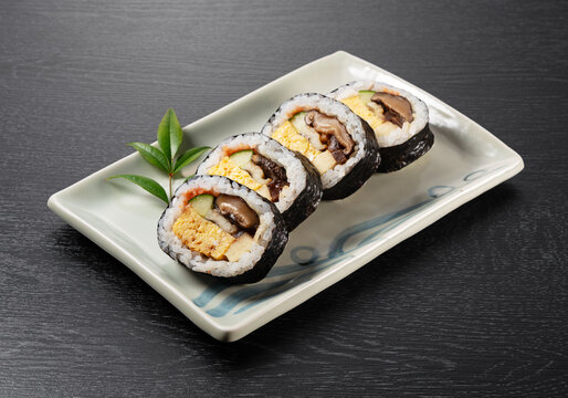 Japanese Futomaki Thick Sushi Rolls on Rectangular Ceramic Plate on Dark Wooden Table