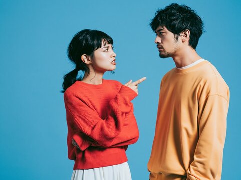 青い背景の前で言い争いをする喧嘩中の若いカップル