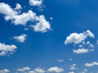 Obraz premium A vibrant horizontal landscape shot of a bright blue sky filled with scattered white cumulus clouds on a clear sunny day