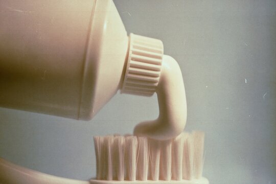 Toothpaste tube squeezing onto brush bristles