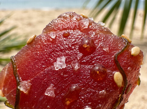 Macro closeup of fresh raw red tuna poke cube seasoned with sea salt crystals sesame and seaweed