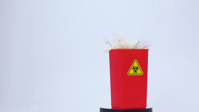 Red clinical biohazard waste container bin bucket holding discarded medical rubbish sharp trash glove for health safety plastic storage