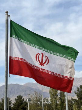 Iranian national flag waving against mountain landscape