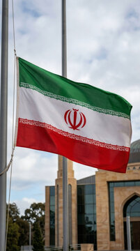 Iranian flag waving outdoors against a modern building backdrop