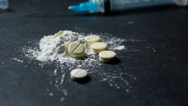 A disposable syringe with white illegal drugs in powder form. Illegal and misused drugs concept