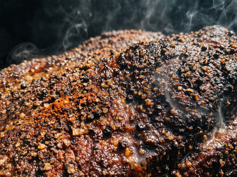 Macro view of seasoned pepper crusted pastrami beef brisket with glistening juices and smoke