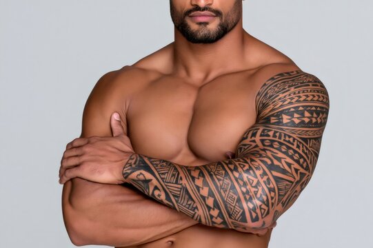 Muscular man showing tribal sleeve tattoo and strength