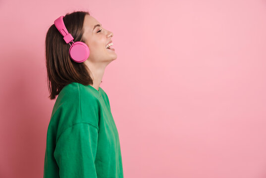 Young woman listening to music wearing pink headphones
