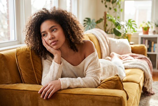 Young woman relaxing on golden sofa in bright sunny living room