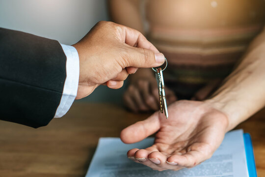 close up view hand of property realtor giving key house to buyer / tenant
