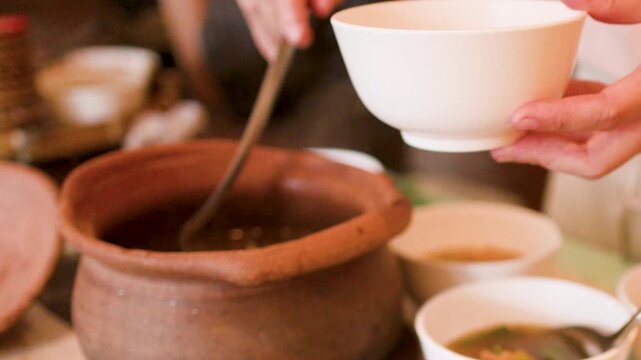 Serving Traditional Thai Isan Soup from a Clay Pot