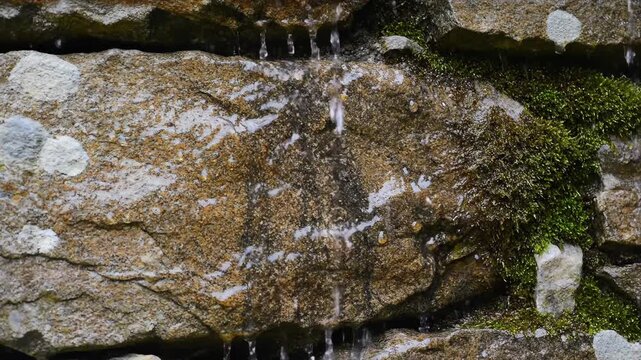 Natural rock fountain with mossy stone water stream and droplets