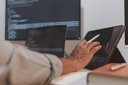 Programmer reviewing source code across laptop, tablet, and monitor while analyzing software architecture. Modern software development workflow featuring coding, debugging, and code inspection.