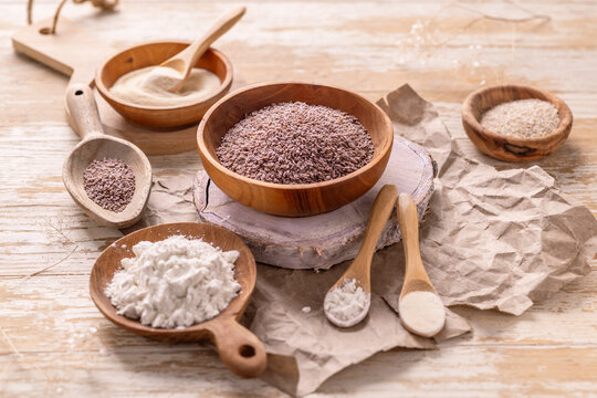 Psyllium husk and powder, xanthan and guar gum in wooden bowls and spoons on a rustic table
