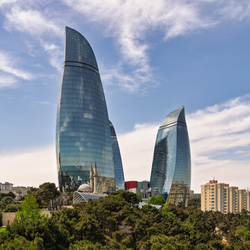Baku, Azerbaijan - May 6, 2024: Flame Towers modern skyscrapers and the Sehitler Mosque showcasing the contrast between historic and contemporary urban architecture against a blue sky