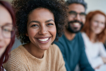 Fototapeta premium Warm, smiling woman with curly hair in a group setting. Bright eyes and joyful expression radiate positivity and connection. Her friends smile, suggesting camaraderie or teamwork
