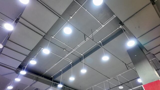 Modern industrial ceiling interior with hanging round LED lights and metal structures.