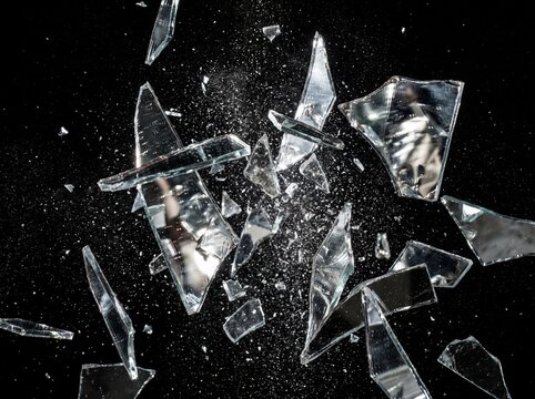 Broken Glass Shards Exploding and Flying in Mid-Air on Black Background